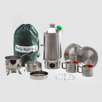 Explore the Kelly Kettle® Ultimate Base Camp Kit by American Reserves, a versatile camping essential with stainless steel kettle, mugs, plates, and a carrying bag labeled Kelly Kettle, ideal for elevating your Outdoor Education experience.